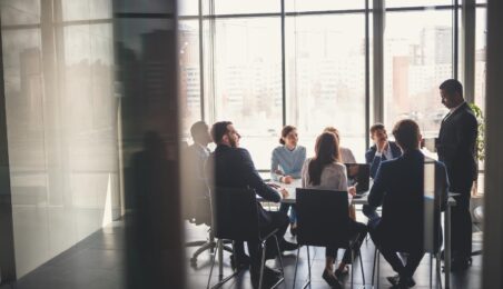 Group of limited partner team members huddling in glass window conference room to discuss private equity investments