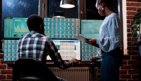 Two people reviewing information on computer screens