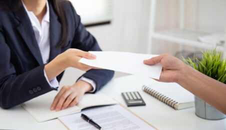 Person in business attire passing a document related to private equity compensation in an office setting.