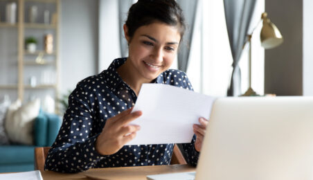 Smiling professional reviewing salary and bonus details on her laptop as part of a compensation management process.